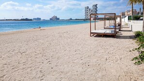 Una playa con una hilera de camas de madera y una palmera.