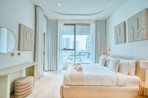 Ein modernes Hotelzimmer mit einem großen Bett, einem Nachttisch, einem Spiegel und Blick auf die Stadt durch große Fenster.