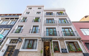 A multi-story hotel with balconies, potted plants, and a sign indicating it is a hotel. - Menar Hotel & Suites (İstanbul)