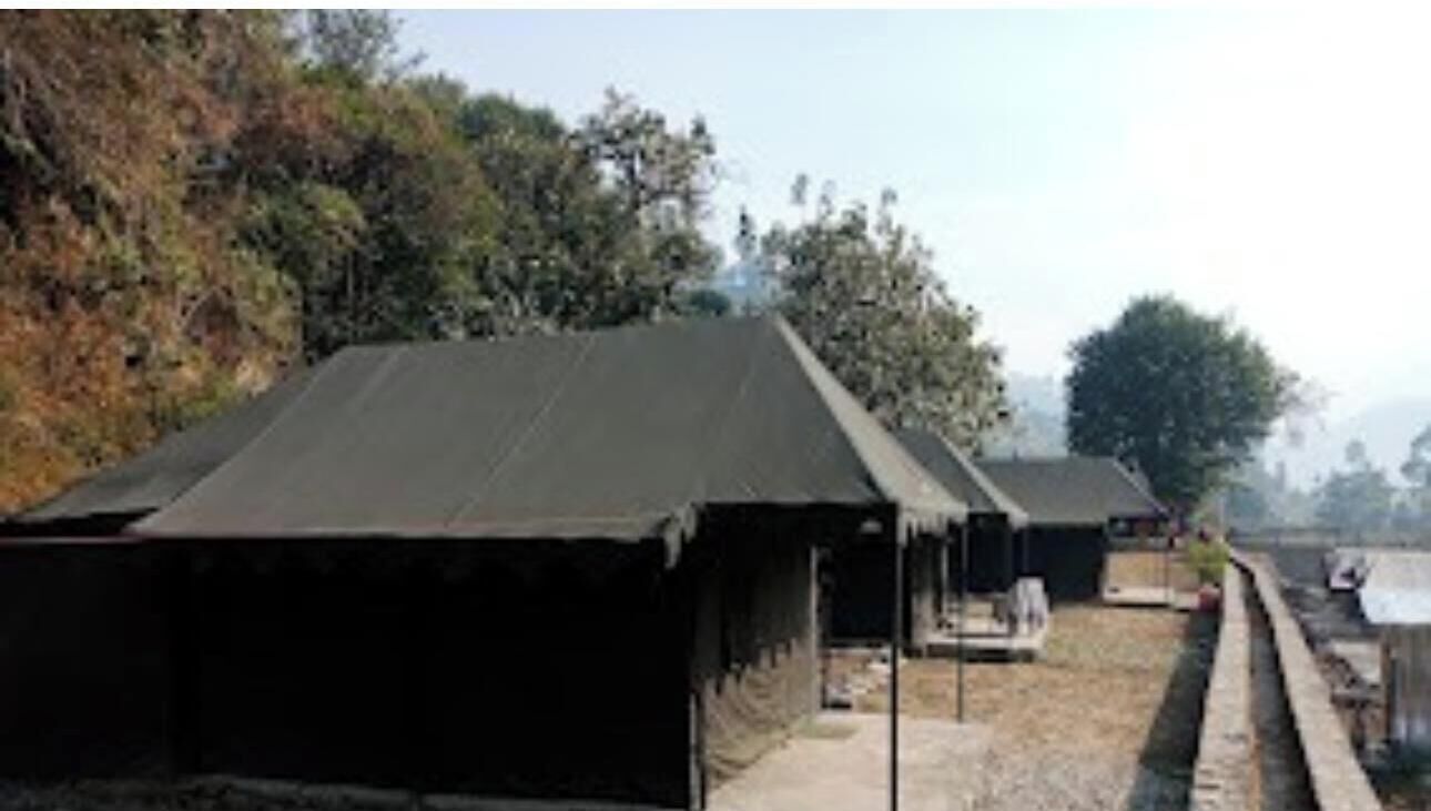 A row of simple, dark-roofed structures with a gravel path in between.