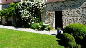 A stone building with a red-tiled roof, a white flowering tree, and a well-maintained lawn. - Chez Cilia Bed and Breakfast - Garden, Parking | Parc Astérix, Senlis, Chantilly (Fresnoy-le-Luat)