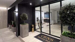 Un ingresso moderno con una palette di colori bianco e nero, una porta in vetro e un tappetino d'ingresso con la scritta "CENT'S Luxury Suites".
