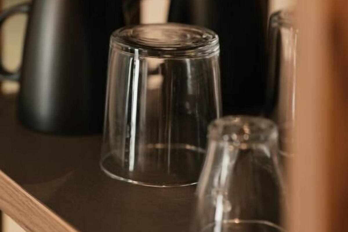 Een plank met verschillende glazen drinkbekers en zwarte mokken.
