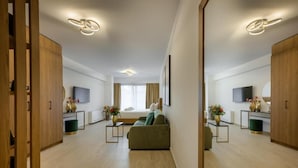 Una habitación de hotel moderna con sofá, televisor, cama y un espejo grande.