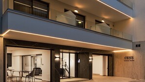 Un hotel de varios pisos con diseño moderno, que presenta fachada de vidrio, una entrada bien iluminada y una recepción visible.