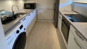 A compact kitchen with a washing machine, microwave, and refrigerator. - Cozy 1-bedroom Apartment in Central Hvidovre, Copenhagen (Hvidovre)
