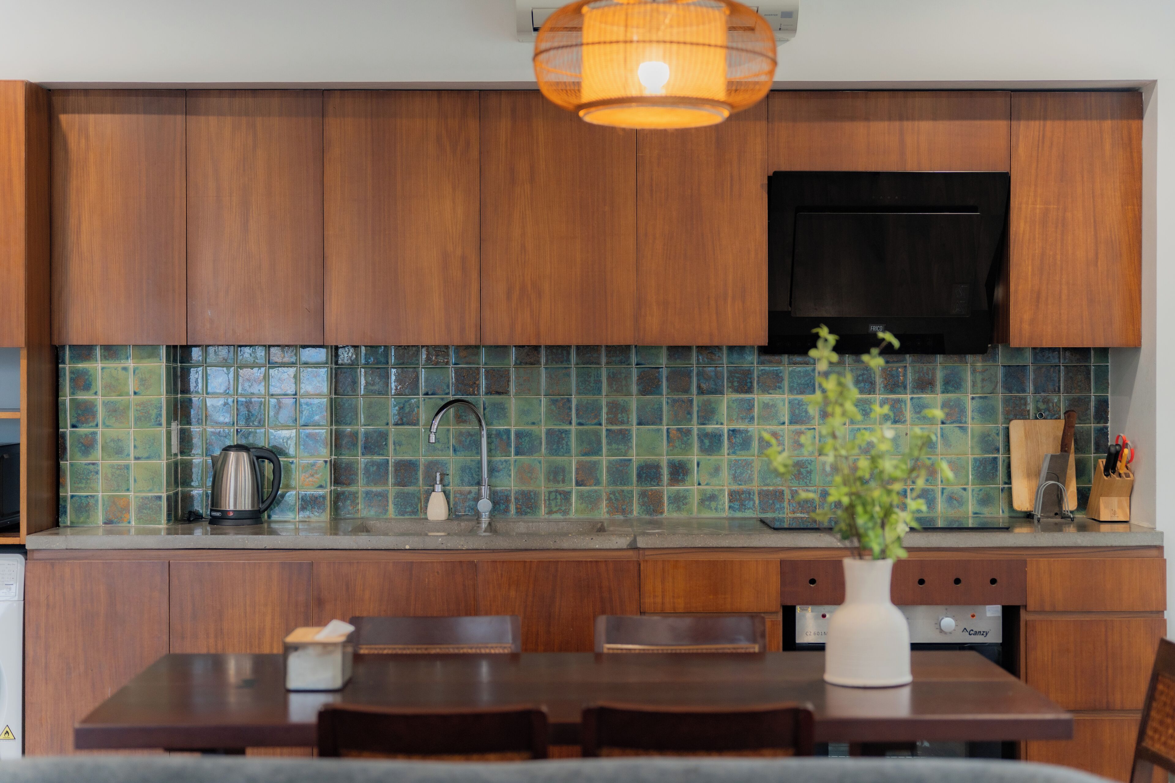 Una cocina moderna con armarios de madera, salpicadero de azulejos y un comedor con mesa y sillas.