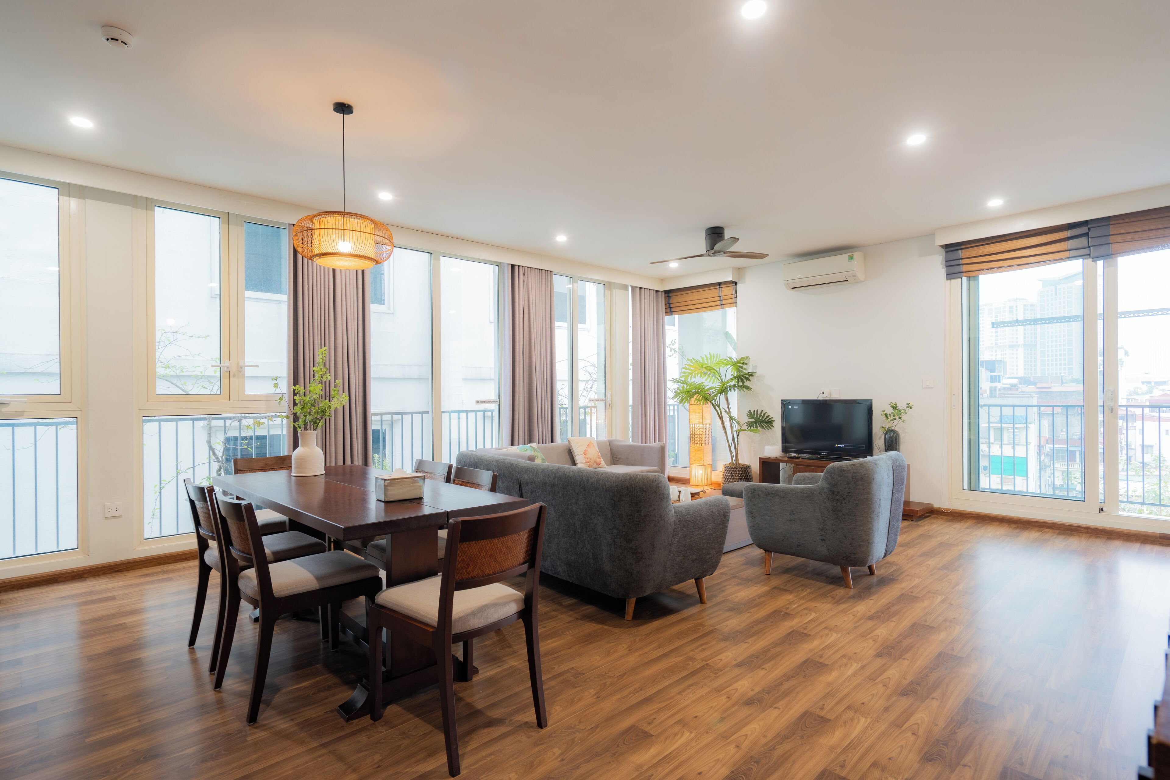 A spacious living area with a dining table, sofas, and a television.