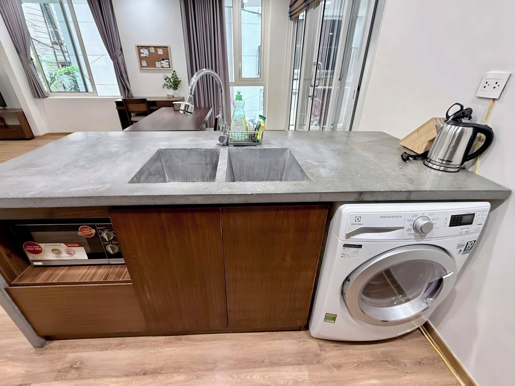 A kitchen with a built-in washer, a sink, and a wooden cabinet.