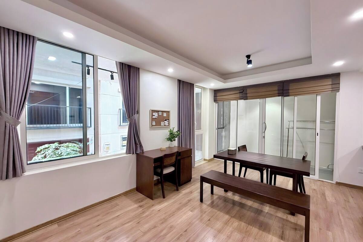 Une pièce moderne avec un plancher en bois, un bureau, une table à manger et un banc.