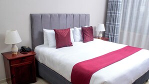 Una habitación de hotel con una cama grande, dos mesitas de noche y una lámpara.