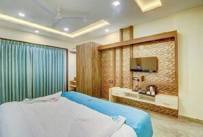 Une chambre d’hôtel comprenant un lit, un téléviseur fixé au mur (qui présente un motif en briques), une table de chevet et une armoire.