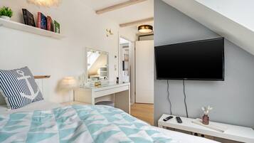 A modern bedroom with a bed, bedside table, TV, and a vanity with a mirror.