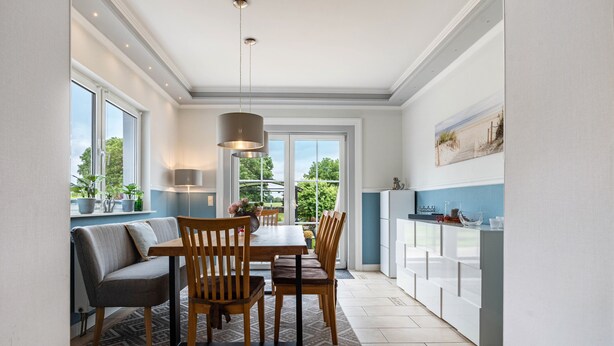 Una cocina moderna con comedor, ventanas amplias y vistas a zonas verdes.