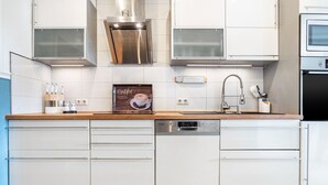 Una cocina moderna con muebles blancos, electrodomésticos de acero inoxidable y encimera de madera.