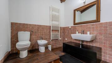 Une salle de bain comprenant des toilettes, un bidet, un lavabo, un miroir et un porte-serviettes.