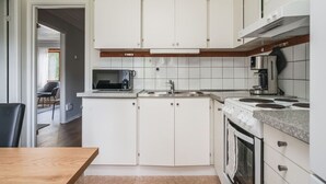 A kitchen with white cabinets, a microwave, a coffee maker, and a stove. - Cozy and Stylish Apartment in Norberg (Norberg)