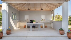 Un patio al aire libre con una mesa, plantas en macetas y una estructura de pérgola.