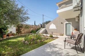 Une terrasse avec une table et des chaises, un mur en pierre et un escalier menant à une porte.