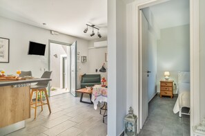 Une cuisine moderne avec un coin bar, une table à manger avec des chaises, un canapé et une petite table avec une lampe.