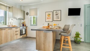 Una cocina moderna con armarios de madera, horno integrado, una isla grande con taburetes de bar y un televisor de pantalla plana montado en la pared.