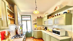 Cozinha com piso de madeira, armários verdes, micro-ondas e diversos utensílios de cozinha.