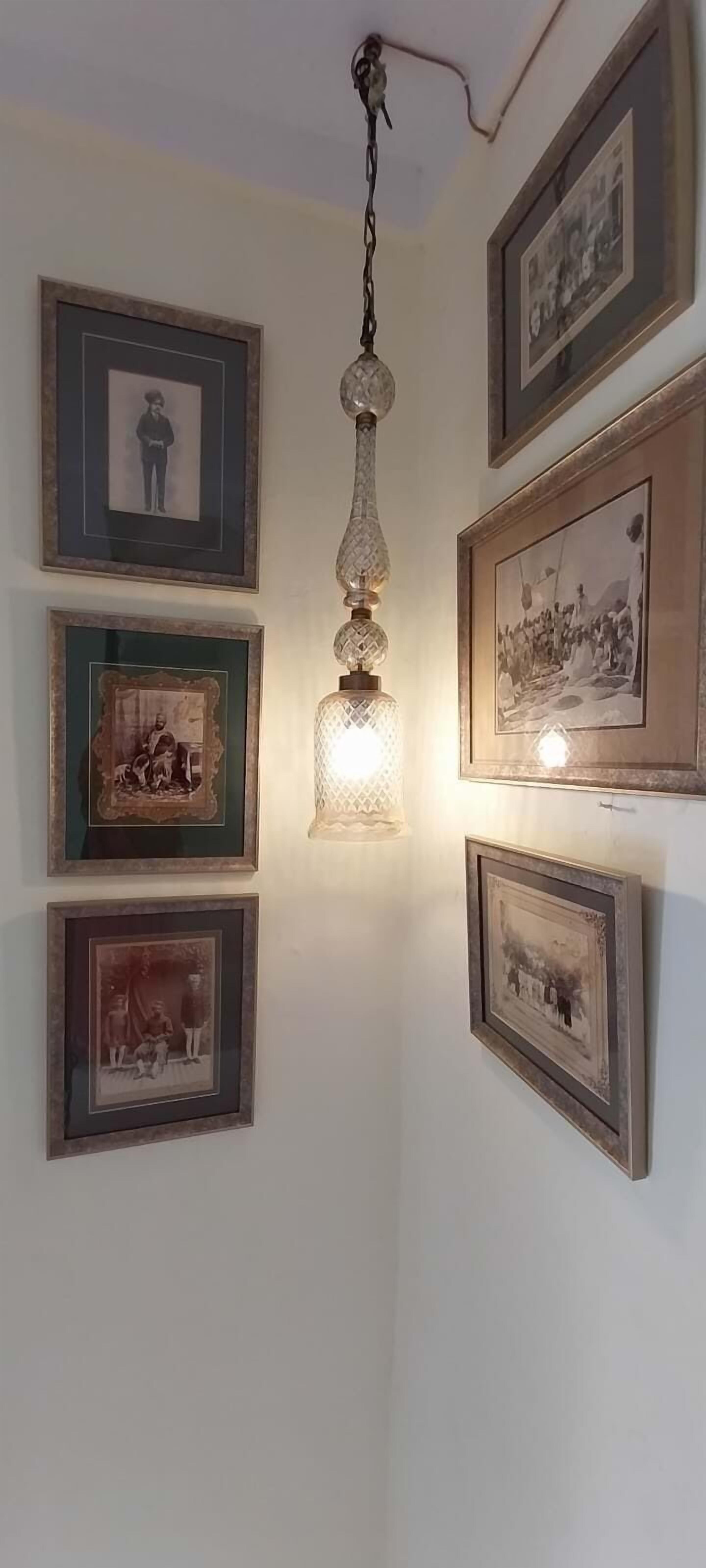 Pared con varias fotografías enmarcadas y una lámpara colgante.