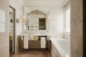 A bathroom with a marble floor, a large mirror, a bathtub, and a sink with two faucets. - Danieli, A Four Seasons Hotel, Venice (Venice)