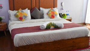 A neatly made bed with a wooden headboard, multiple pillows, and a red throw blanket. - Hotel Rosh Villa (Manali)