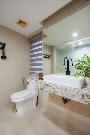 Une salle de bain moderne avec des toilettes, un lavabo doté d’un robinet noir et un miroir au-dessus du lavabo.