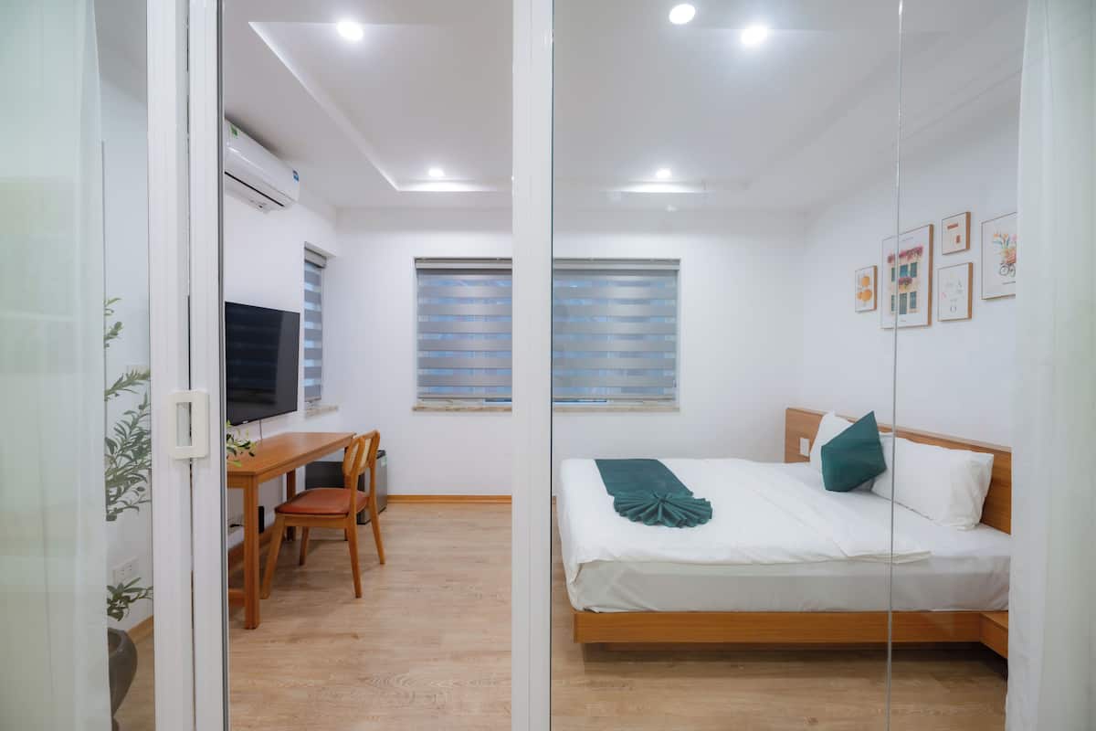 Un dormitorio moderno con una cama de madera, un escritorio con una silla y un televisor.