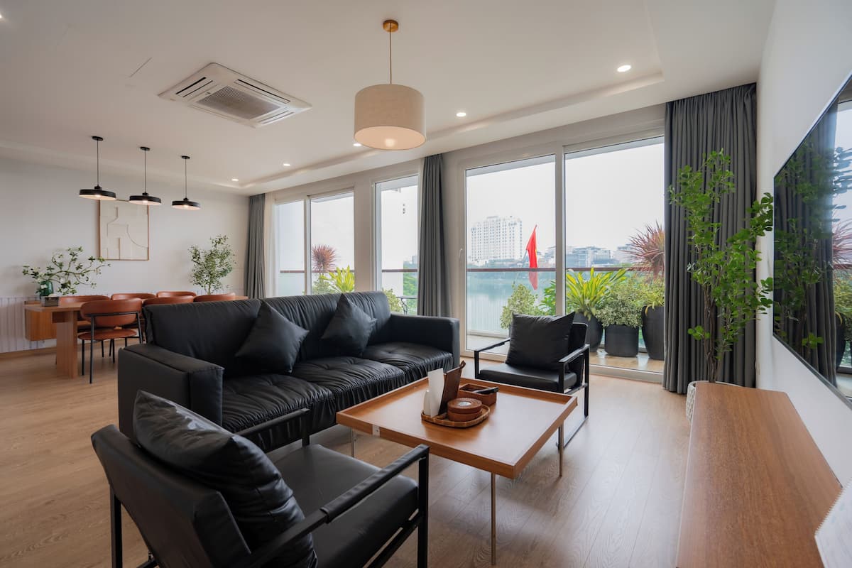 Una sala de estar moderna con un sofá de cuero negro, una mesa de centro de madera y un comedor con una mesa y sillas de madera.