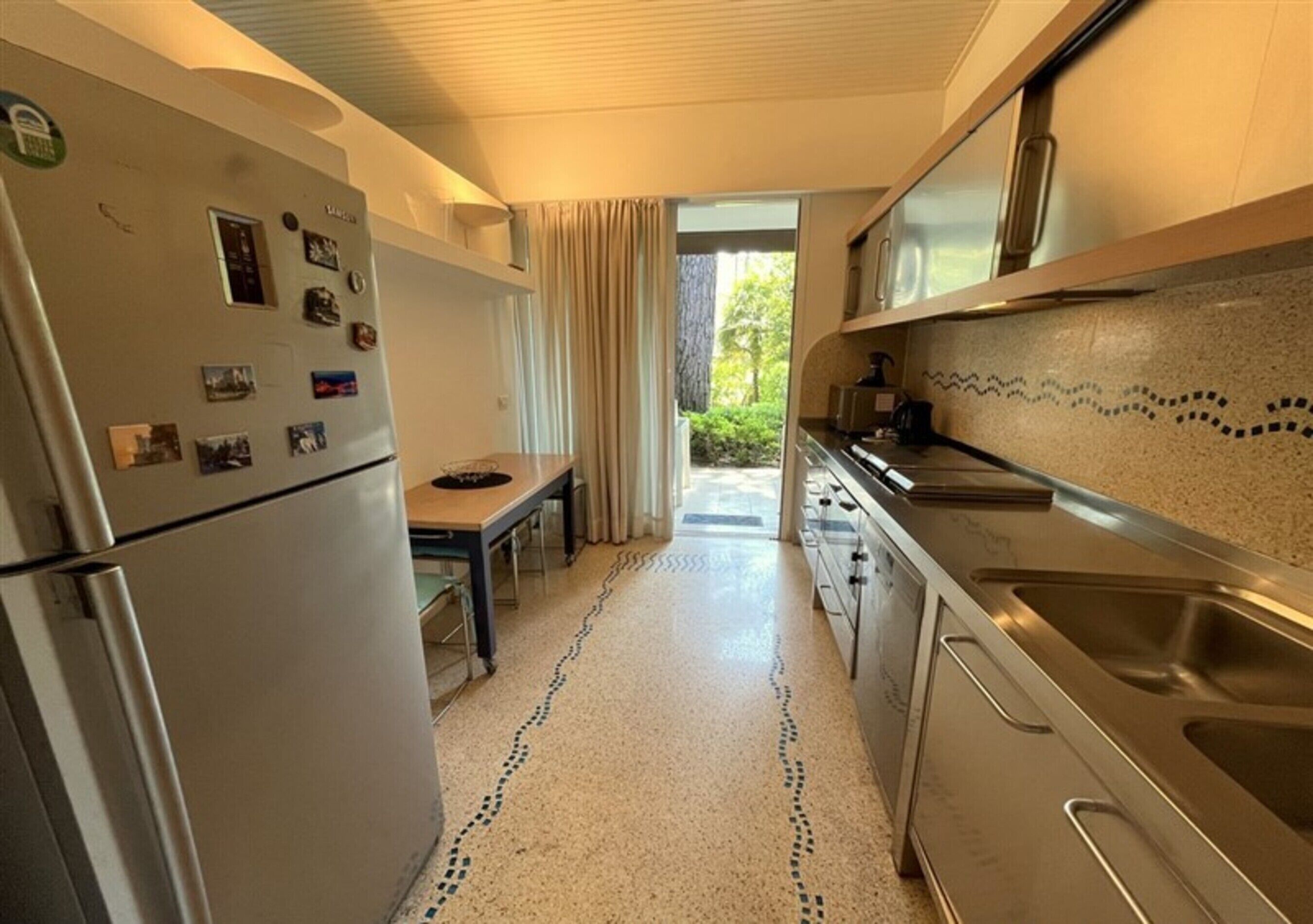 A compact kitchen with a refrigerator, a dining table, and a sink.