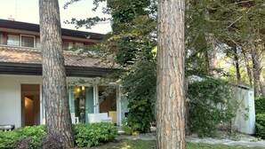 A modern house with a covered patio, surrounded by mature trees and well-maintained landscaping. - Charming and Tastefully Furnished Villa Steps From the sea (Lignano Sabbiadoro)