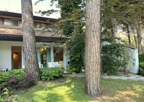 A modern house with a covered patio, surrounded by mature trees and well-maintained landscaping. - Charming and Tastefully Furnished Villa Steps From the sea (Lignano Sabbiadoro)