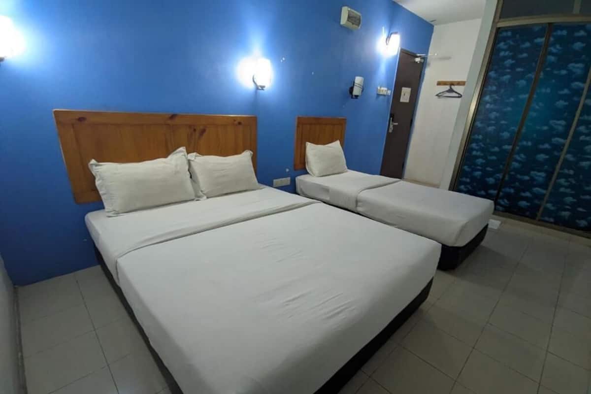 A room with two beds, a blue wall, and a door with a blue patterned curtain.