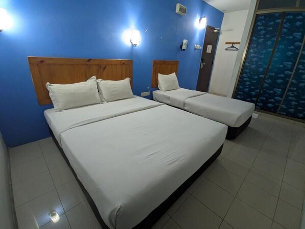 A room with two beds, a blue wall, and a door with a blue patterned curtain. - Midah Inn Puchong (Seri Kembangan)