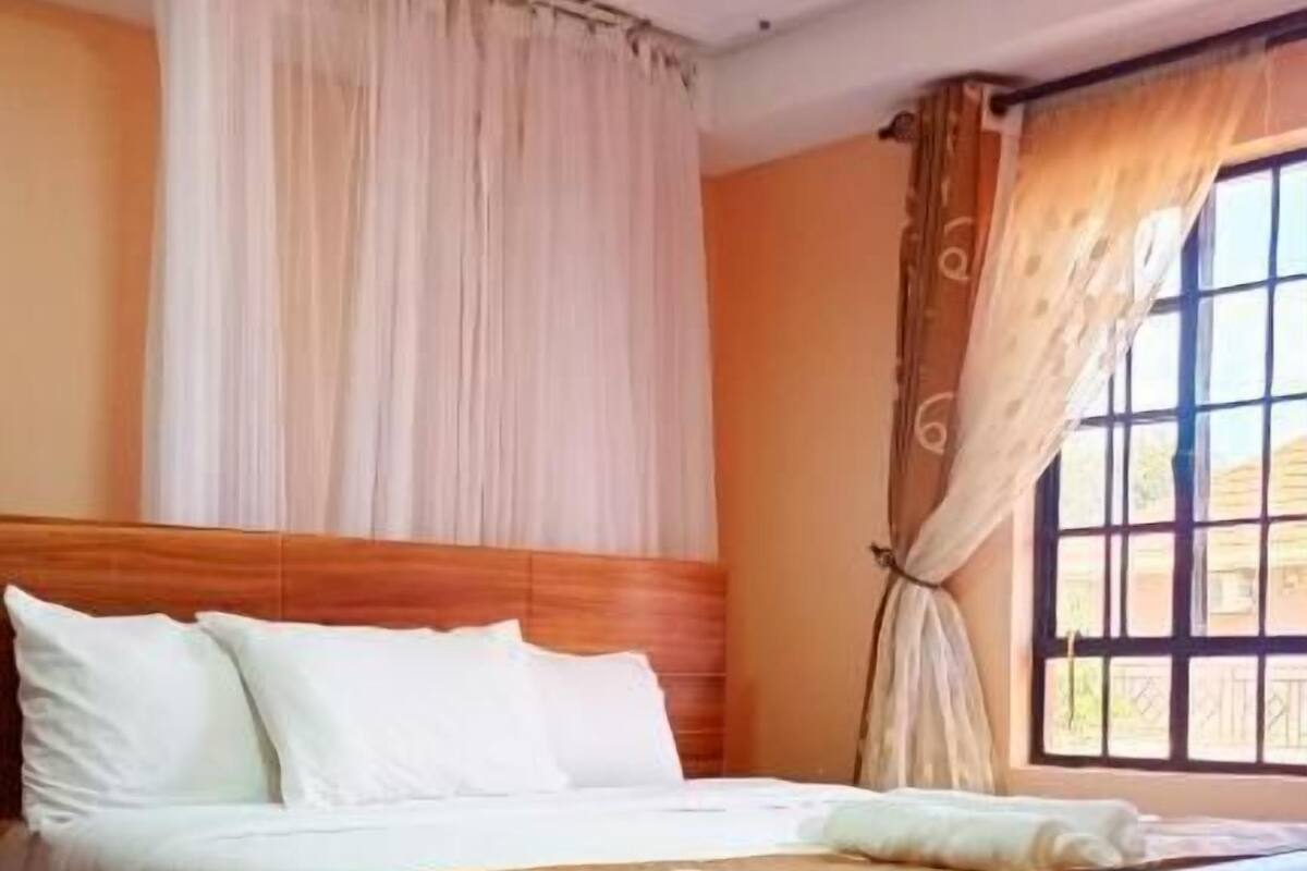 Une chambre d’hôtel avec un grand lit, des rideaux et une fenêtre.