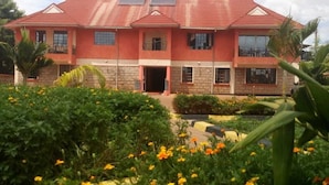 A two-story house with a red roof, multiple windows, and a front entrance. - Savannah Paradise Hotel Makindu (Makindu)