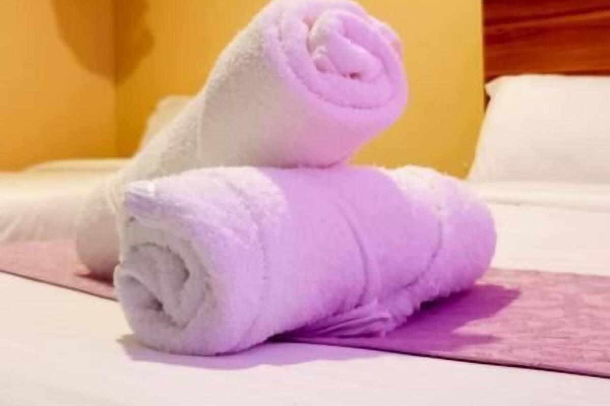 Une chambre d’hôtel avec un lit, une tête de lit blanche et un mur blanc.