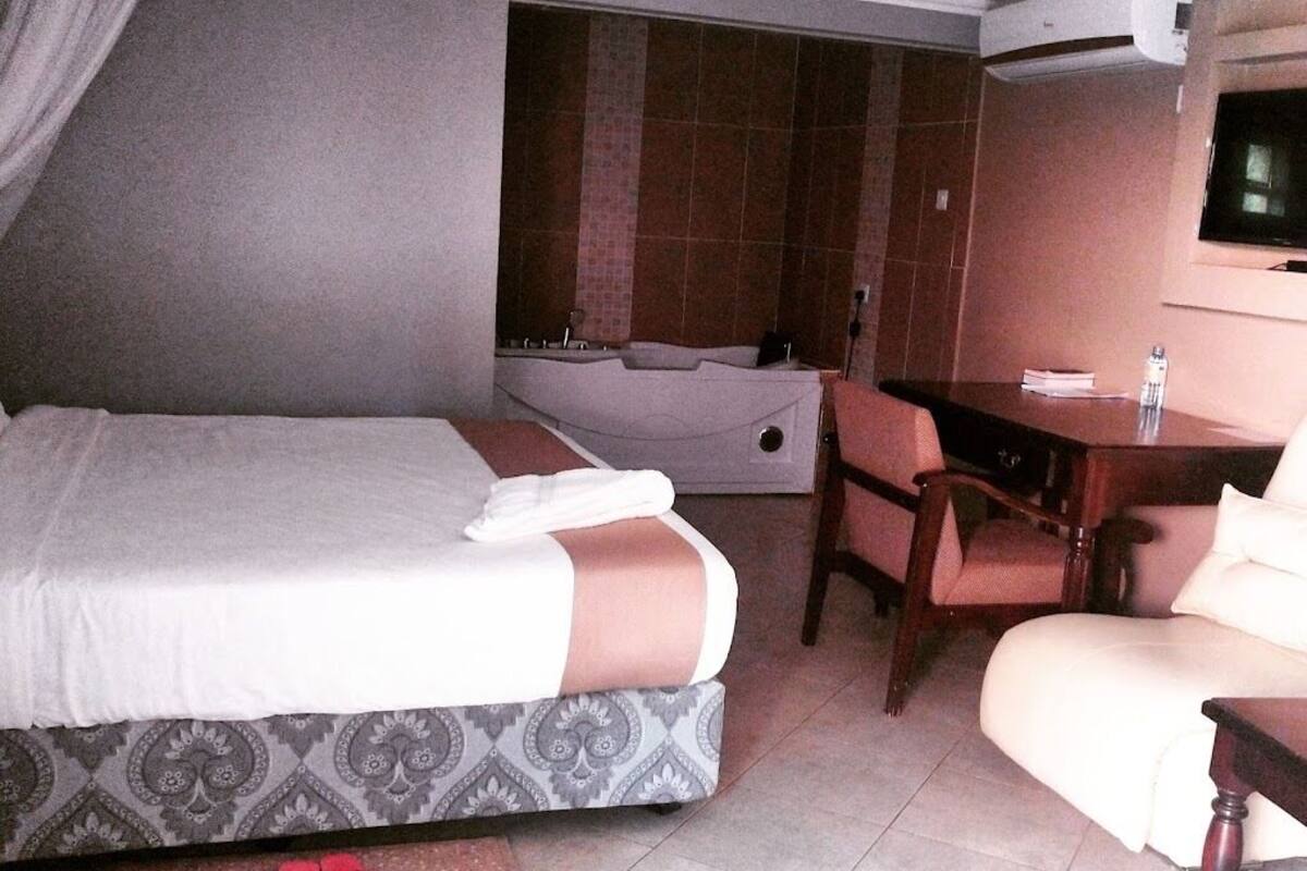 Une chambre d’hôtel équipée d’un lit, d’un bureau, d’une chaise, d’une baignoire et d’un téléviseur.