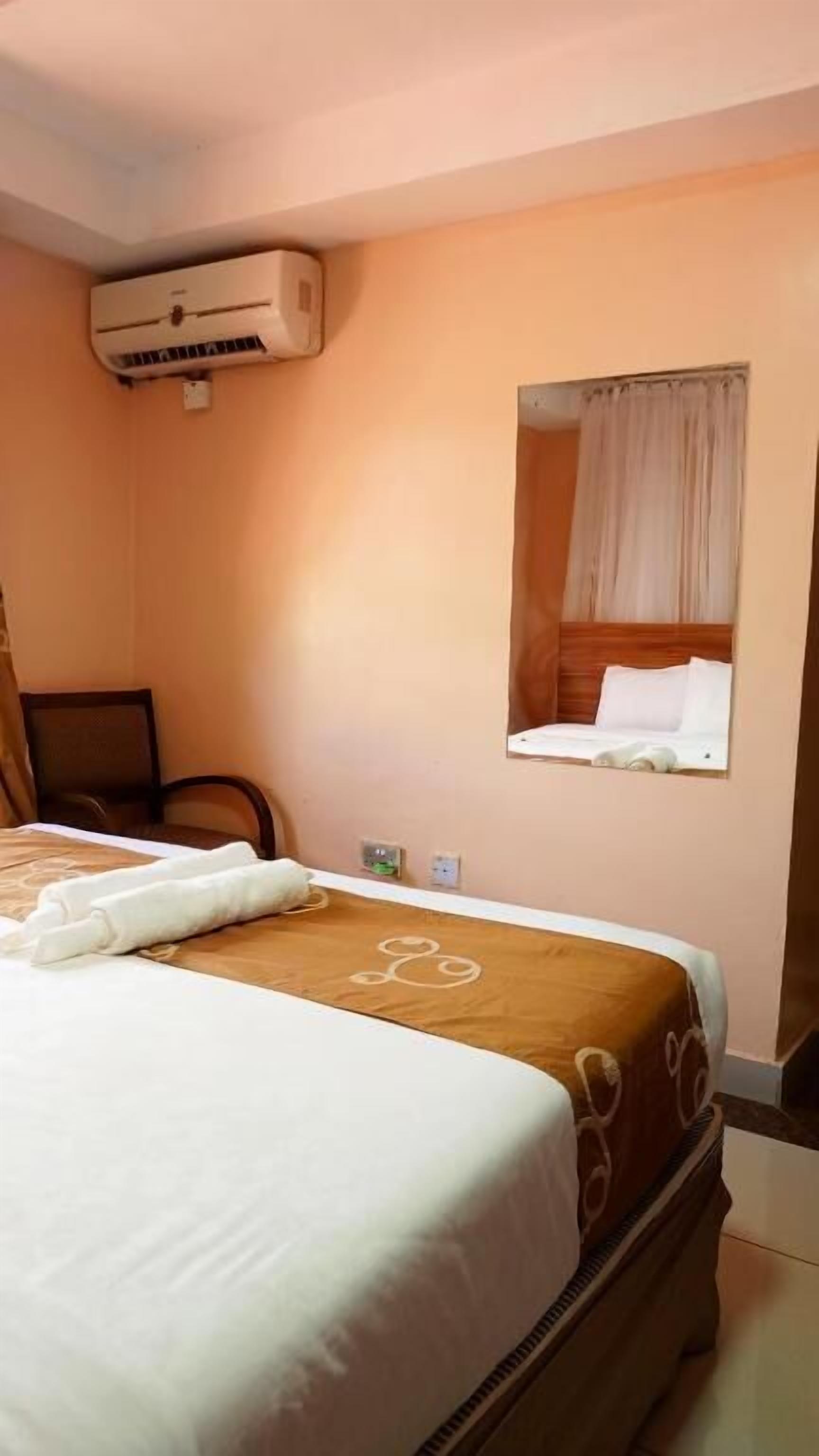 Een hotelkamer met een bed, een stoel, een klein tafeltje en een spiegel aan de muur.