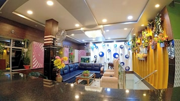 A lobby with a blue sofa, a coffee table, and a fan.