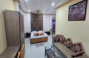 A compact hotel room with a bed, a sofa, a small table, and a mirror.
