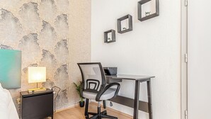 A small, modern room with a desk, chair, and a TV on a nightstand. - Cozy 2BR Apartment Near Prater Danube (Vienna)