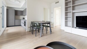 A modern kitchen with a dining area, built-in shelving, and a flat-screen TV. - GuestHost - Spacious and modern 75 square meters apartment, perfect for six people, located on the second floor of a building with an elevator (NOT accessible to guests with disabilities).The property is located in a quiet area, allowing our guests to ex (Milan)