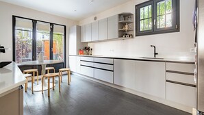 Una cocina moderna con armarios blancos, encimera negra y ventana con vistas a un jardín.