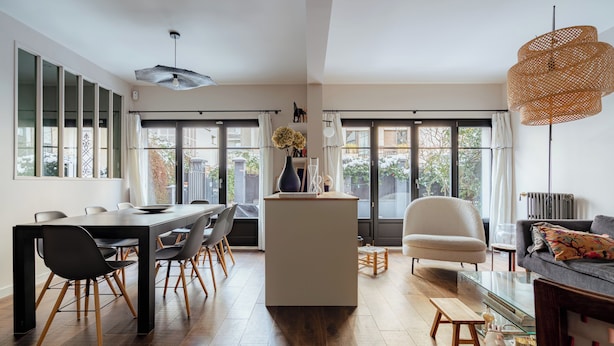 Un espacio moderno de estar con comedor, una isla central y una zona de asientos con sofá y sillones.