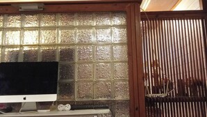 A room with a bed, a TV on a stand, a window with a decorative grid, and a wooden slat partition. - Spacious City-view Apartment With Modern Amenities in Krung Thep (Bangkok)