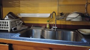 A kitchen with a stainless steel sink, a dish rack, and a bottle of dish soap. - Spacious City-view Apartment With Modern Amenities in Krung Thep (Bangkok)